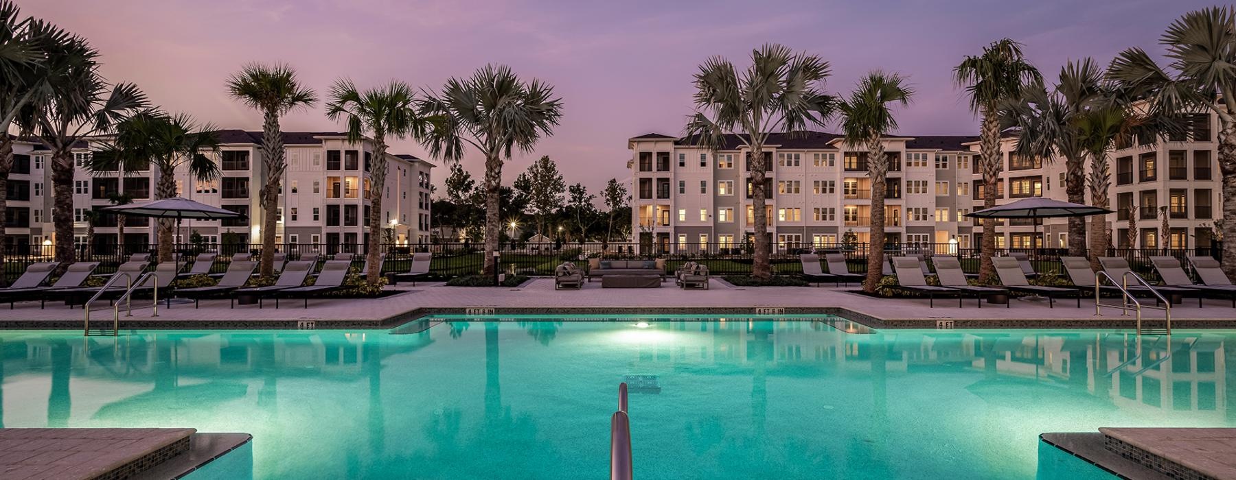 a pool with palm trees and buildings in the background